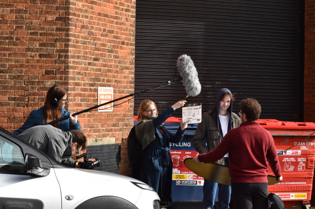 Kara holding a clapperboard on the film set of Petalled Apologies.